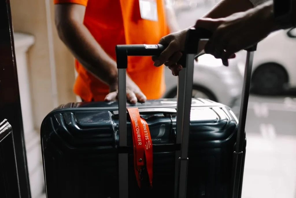Client holding a suitcase handle as a Selena courier takes over the luggage at a London doorway