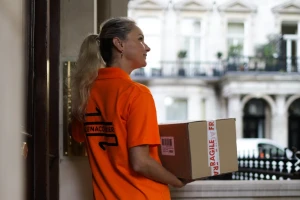 Selena courier waiting at a London front door with a parcel marked fragile