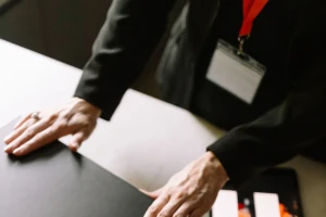 Hands resting on a black presentation box beside a tablet while a delivery is planned