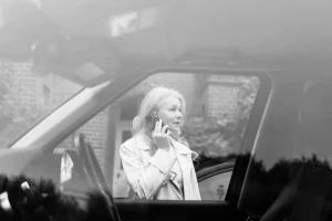 Elena Ermakova, founder of Selena Courier Service, standing beside a car and speaking on the phone