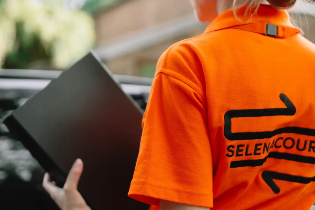 Selena courier in branded uniform holding a delivery box