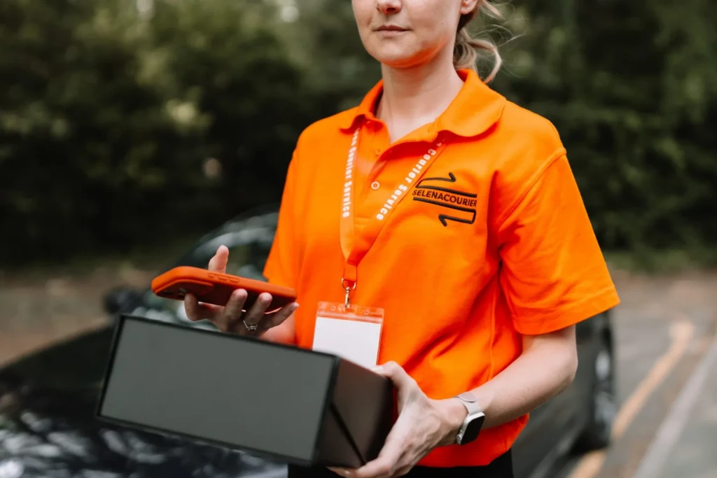 Courier holding a delivery box and phone during a London round