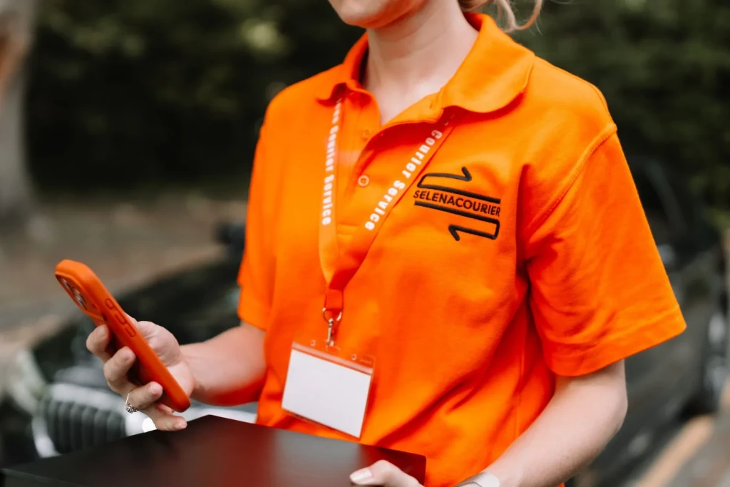 Courier confirming a delivery on a phone at the vehicle