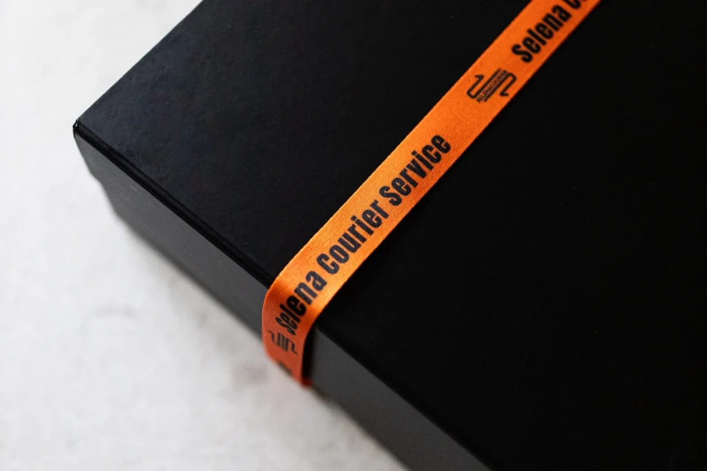 Black Selena Courier box sealed with the orange branded ribbon