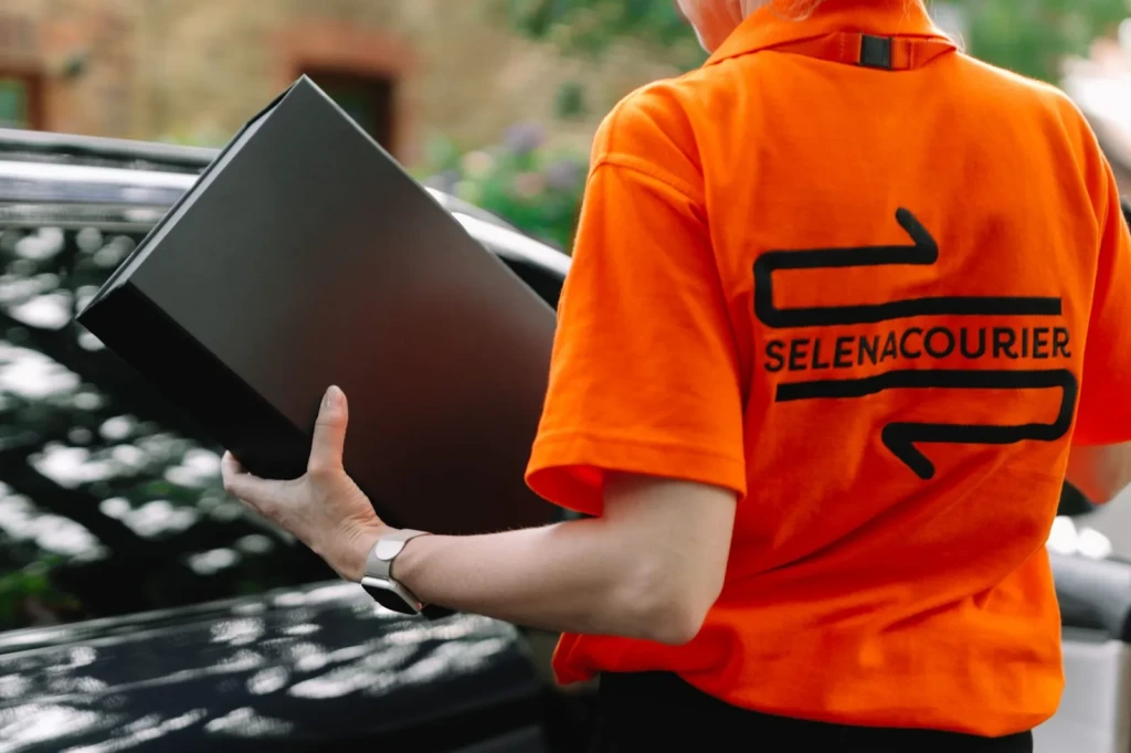 Selena courier carrying a branded box to the delivery vehicle