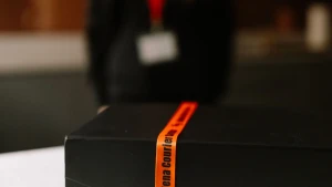 A prepared box sealed with Selena Courier Service tape on a counter, with a coordinator in the background