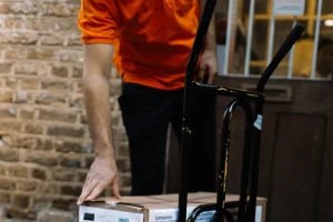 Selena courier moving a trolley of boxes at a delivery door