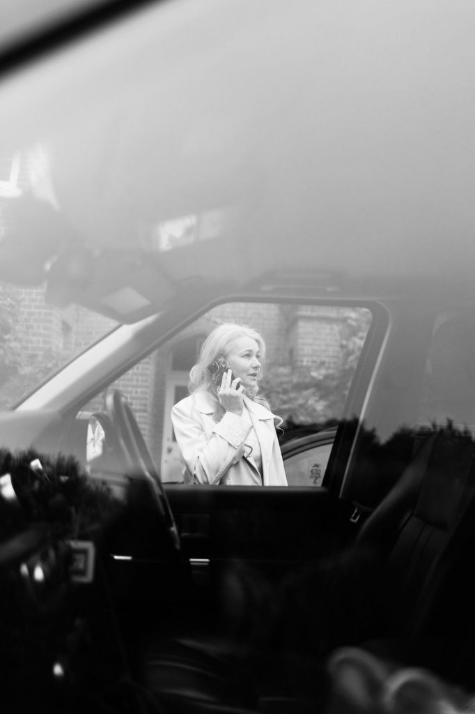 Elena Ermakova, founder of Selena Courier Service, standing beside a car and speaking on the phone