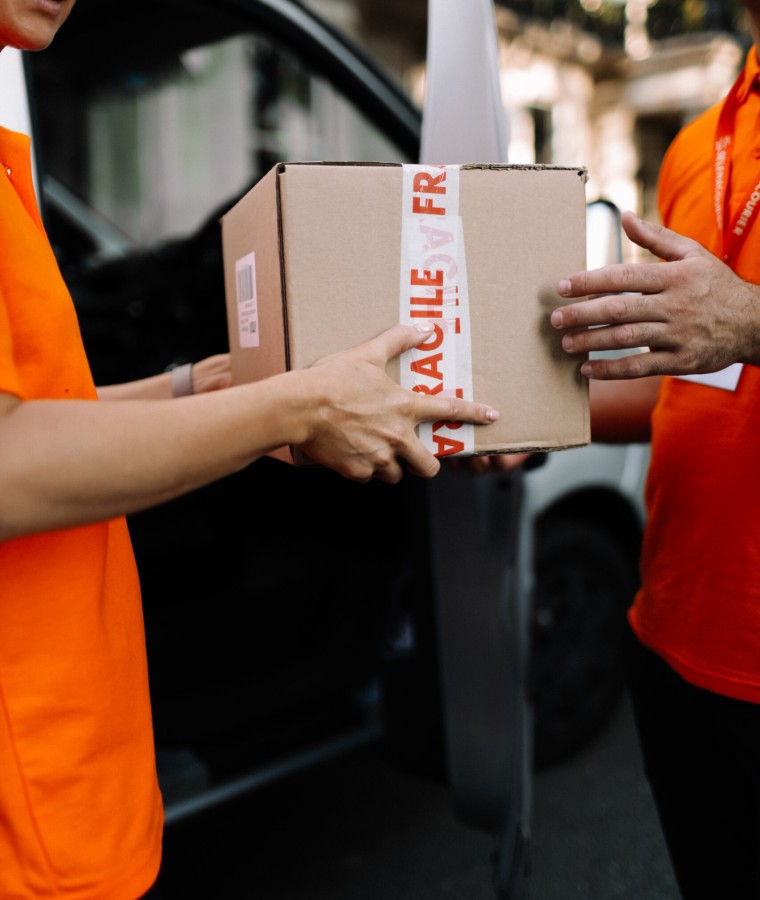 Selena courier handing a fragile-marked box from the van to a client