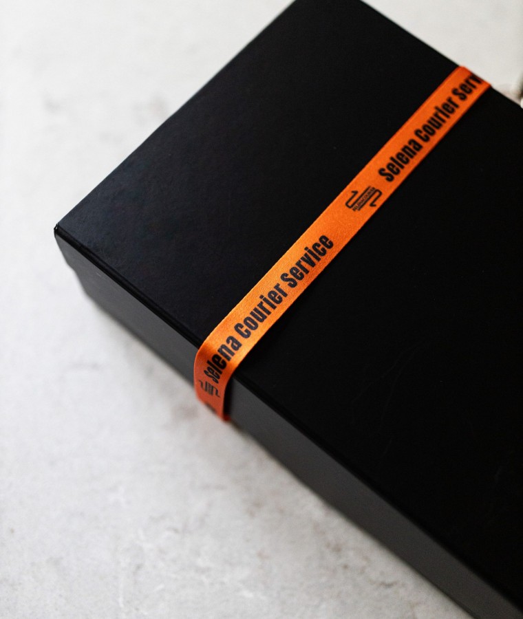 Black presentation box secured with orange Selena Courier ribbon