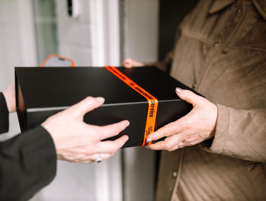 Black presentation box passed carefully between courier and recipient