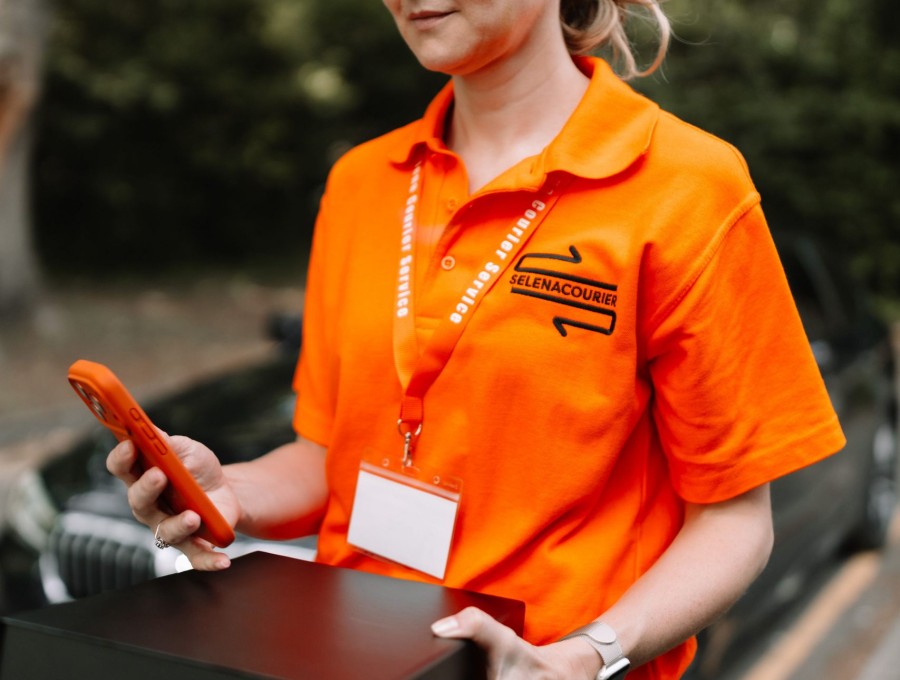 Courier confirming a delivery on a phone at the vehicle