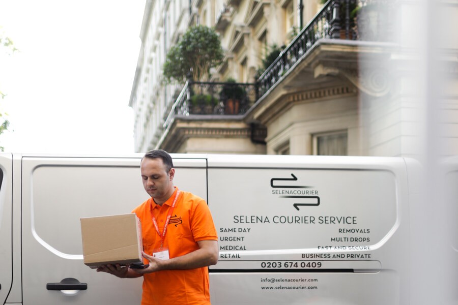 Selena courier carrying a parcel beside a branded vehicle in London