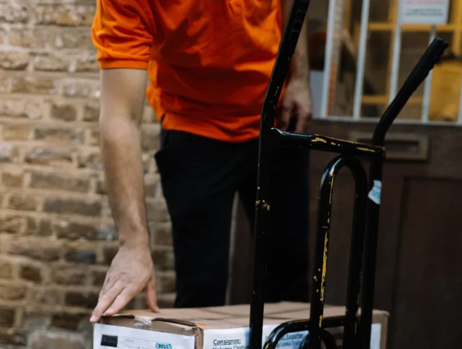 Selena courier moving a trolley of boxes at a delivery door